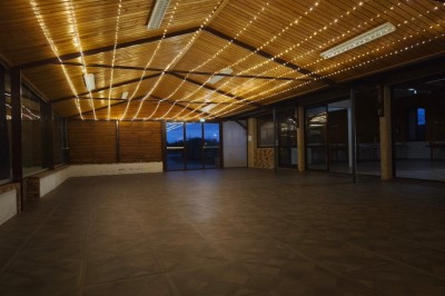 Grande maison en pierre entourée de verdure, avec une cour ensoleillée et des arbres en arrière-plan.