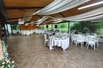 Grande maison en pierre entourée de verdure, avec une cour ensoleillée et des arbres en arrière-plan.