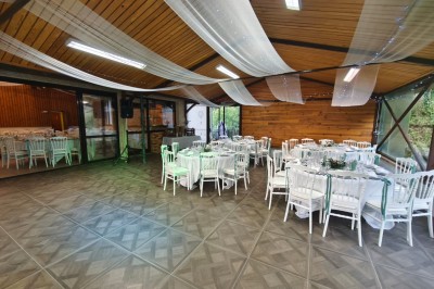 Grande maison en pierre entourée de verdure, avec une cour ensoleillée et des arbres en arrière-plan.