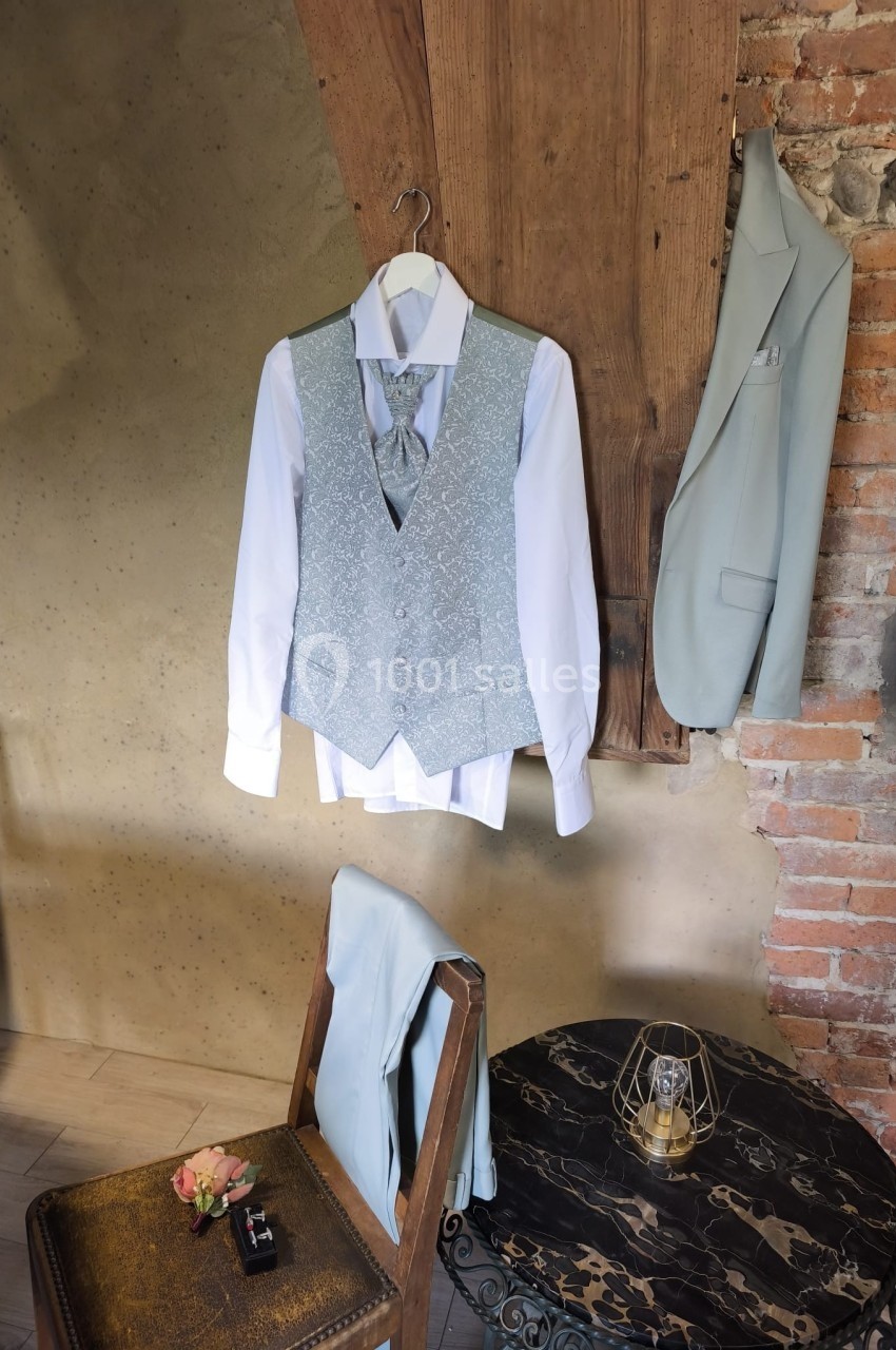 Tenue de mariage composée d'une chemise blanche, d'un gilet gris, d'une cravate assortie et d'une veste suspendue.