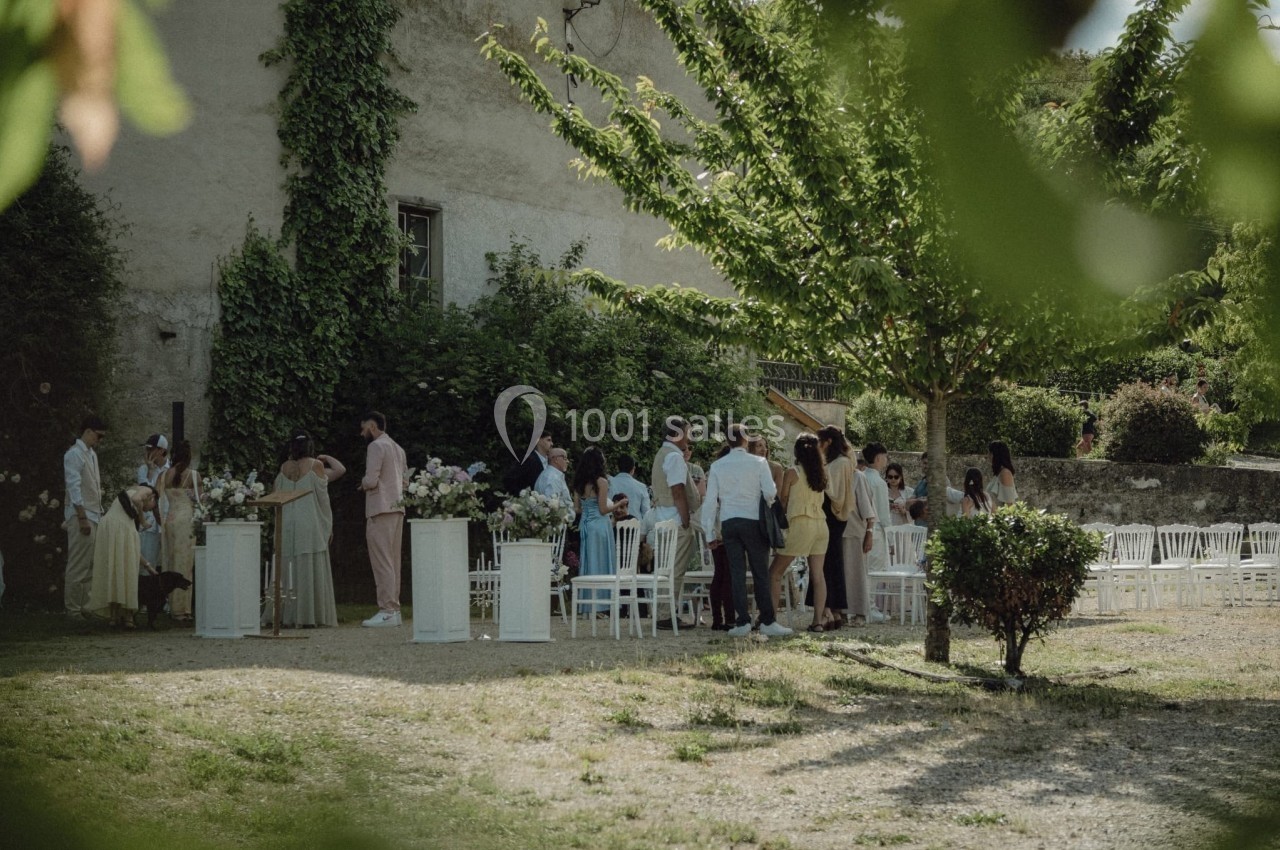 Groupe de personnes rassemblées dans un jardin, près de chaises blanches et de décorations florales.