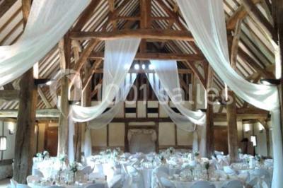 Table ronde élégamment dressée avec nappes blanches, verres, couverts, pains et décoration florale dans une salle de…