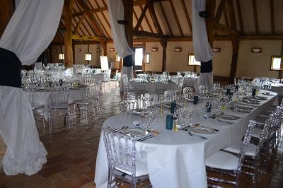 Table ronde élégamment dressée avec nappes blanches, verres, couverts, pains et décoration florale dans une salle de…