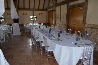 Table ronde élégamment dressée avec nappes blanches, verres, couverts, pains et décoration florale dans une salle de…