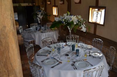 Table ronde élégamment dressée avec nappes blanches, verres, couverts, pains et décoration florale dans une salle de…