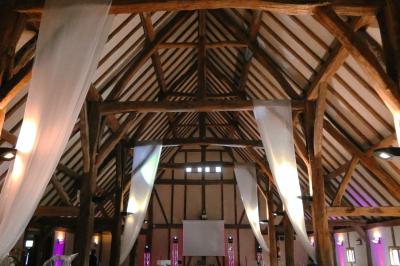 Table ronde élégamment dressée avec nappes blanches, verres, couverts, pains et décoration florale dans une salle de…