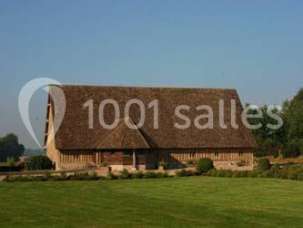 Table ronde élégamment dressée avec nappes blanches, verres, couverts, pains et décoration florale dans une salle de…