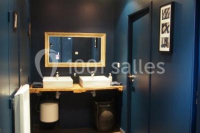 Deux lits simples avec linge à motifs floraux dans une chambre aux murs roses, éclairée par des lampes de chevet.