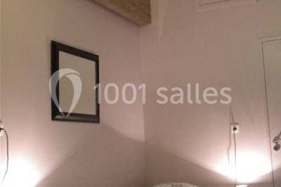 Deux lits simples avec linge à motifs floraux dans une chambre aux murs roses, éclairée par des lampes de chevet.