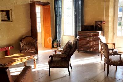 Pressoir ancien en bois dans une pièce avec murs en pierre, plafond à poutres apparentes et sol en parquet.