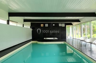 Pressoir ancien en bois dans une pièce avec murs en pierre, plafond à poutres apparentes et sol en parquet.