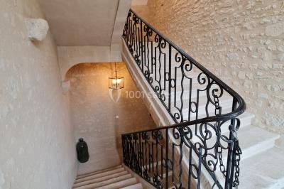 Pressoir ancien en bois dans une pièce avec murs en pierre, plafond à poutres apparentes et sol en parquet.