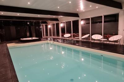 Pressoir ancien en bois dans une pièce avec murs en pierre, plafond à poutres apparentes et sol en parquet.