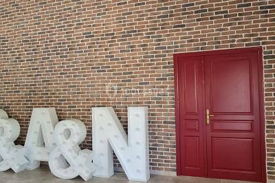 Pressoir ancien en bois dans une pièce avec murs en pierre, plafond à poutres apparentes et sol en parquet.
