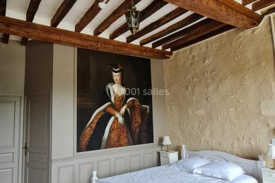Pressoir ancien en bois dans une pièce avec murs en pierre, plafond à poutres apparentes et sol en parquet.