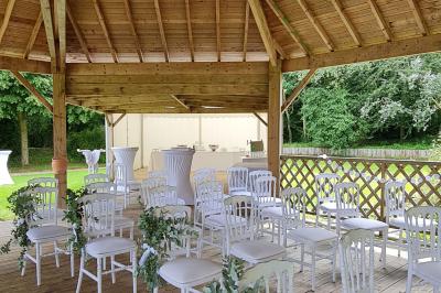 Pressoir ancien en bois dans une pièce avec murs en pierre, plafond à poutres apparentes et sol en parquet.