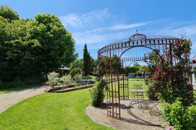 Pressoir ancien en bois dans une pièce avec murs en pierre, plafond à poutres apparentes et sol en parquet.