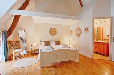 Pressoir ancien en bois dans une pièce avec murs en pierre, plafond à poutres apparentes et sol en parquet.