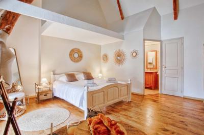 Pressoir ancien en bois dans une pièce avec murs en pierre, plafond à poutres apparentes et sol en parquet.