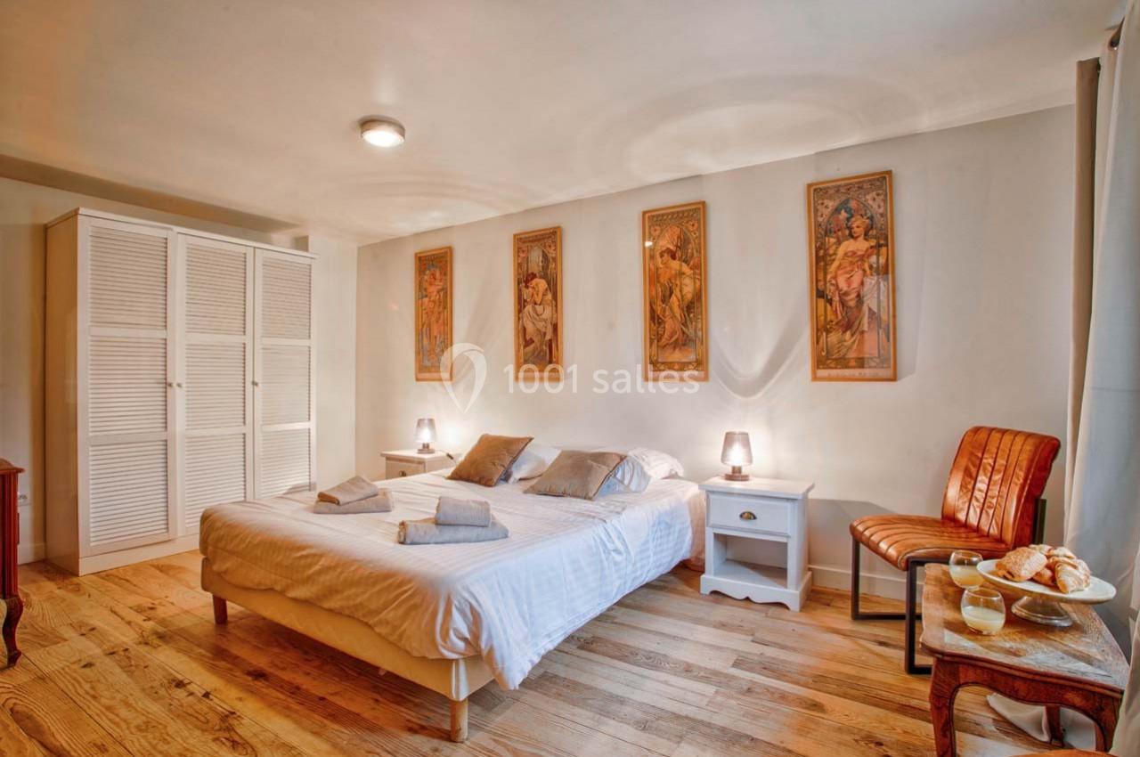 Chambre lumineuse avec lit double, parquet en bois, meubles simples et décorations murales artistiques.