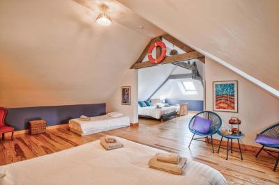 Pressoir ancien en bois dans une pièce avec murs en pierre, plafond à poutres apparentes et sol en parquet.