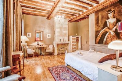 Pressoir ancien en bois dans une pièce avec murs en pierre, plafond à poutres apparentes et sol en parquet.