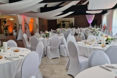 Pressoir ancien en bois dans une pièce avec murs en pierre, plafond à poutres apparentes et sol en parquet.