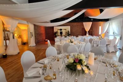 Pressoir ancien en bois dans une pièce avec murs en pierre, plafond à poutres apparentes et sol en parquet.