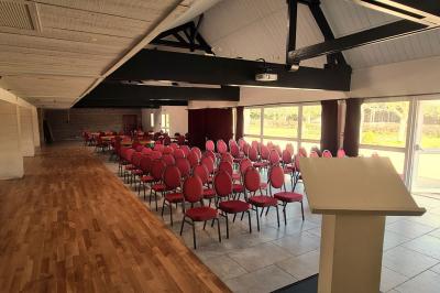 Pressoir ancien en bois dans une pièce avec murs en pierre, plafond à poutres apparentes et sol en parquet.