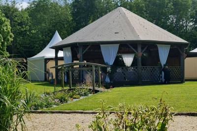 Pressoir ancien en bois dans une pièce avec murs en pierre, plafond à poutres apparentes et sol en parquet.