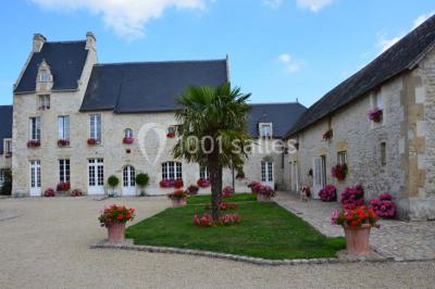 Pressoir ancien en bois dans une pièce avec murs en pierre, plafond à poutres apparentes et sol en parquet.