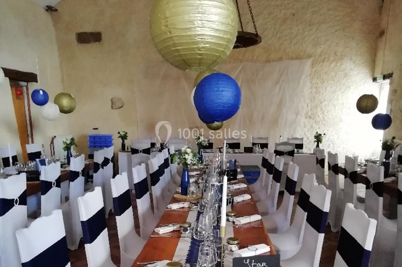 Salle de réception décorée avec des lanternes suspendues et des tables dressées pour un événement festif.