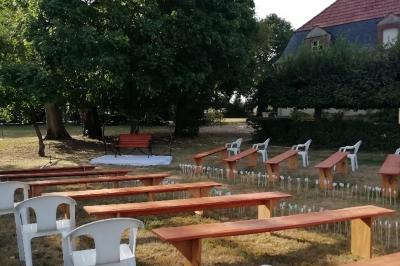 Grande maison blanche entourée d'arbres et d'une pelouse verte sous un ciel légèrement nuageux.