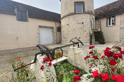 Chambre avec poutres apparentes, lit simple, armoire ancienne, bureau, chaise et fenêtre ouverte sur l'extérieur.