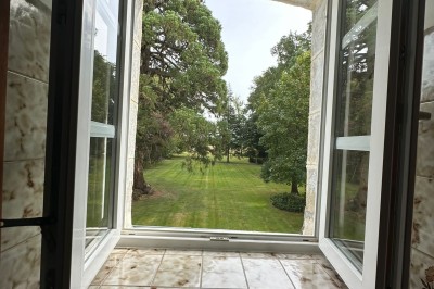 Chambre avec poutres apparentes, lit simple, armoire ancienne, bureau, chaise et fenêtre ouverte sur l'extérieur.