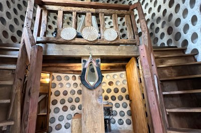 Chambre avec poutres apparentes, lit simple, armoire ancienne, bureau, chaise et fenêtre ouverte sur l'extérieur.