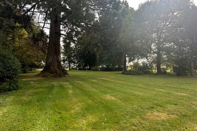 Chambre avec poutres apparentes, lit simple, armoire ancienne, bureau, chaise et fenêtre ouverte sur l'extérieur.