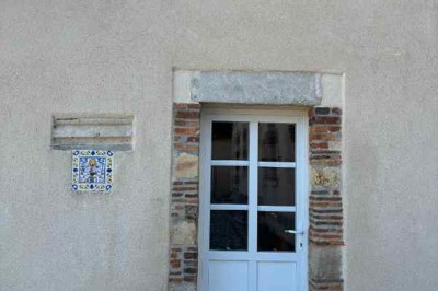 Cour pavée avec un puits en pierre au premier plan, entouré de bacs végétalisés, et bâtiments en arrière-plan.