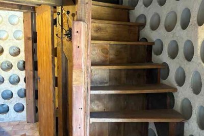 Cour pavée avec un puits en pierre au premier plan, entouré de bacs végétalisés, et bâtiments en arrière-plan.