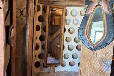 Cour pavée avec un puits en pierre au premier plan, entouré de bacs végétalisés, et bâtiments en arrière-plan.