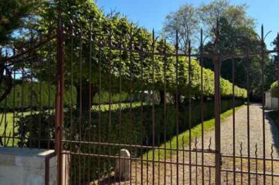 Cour pavée avec un puits en pierre au premier plan, entouré de bacs végétalisés, et bâtiments en arrière-plan.