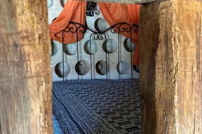 Cour pavée avec un puits en pierre au premier plan, entouré de bacs végétalisés, et bâtiments en arrière-plan.