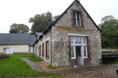 Champ verdoyant bordé d'arbres en automne, avec un grand bâtiment blanc visible à l'arrière-plan.
