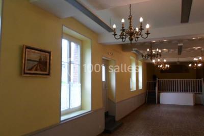 Champ verdoyant bordé d'arbres en automne, avec un grand bâtiment blanc visible à l'arrière-plan.