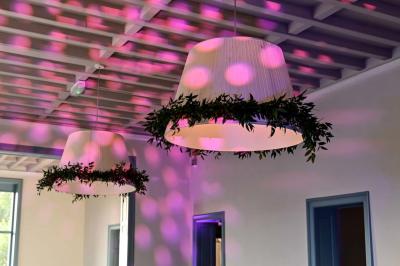 Des lanternes lumineuses flottent dans la nuit près d'une grande maison éclairée en bleu, entourée de personnes.