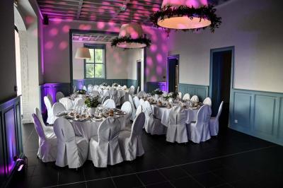 Des lanternes lumineuses flottent dans la nuit près d'une grande maison éclairée en bleu, entourée de personnes.