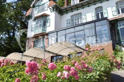 Des lanternes lumineuses flottent dans la nuit près d'une grande maison éclairée en bleu, entourée de personnes.