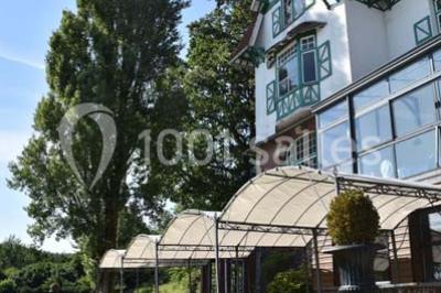 Des lanternes lumineuses flottent dans la nuit près d'une grande maison éclairée en bleu, entourée de personnes.
