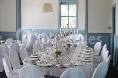 Des lanternes lumineuses flottent dans la nuit près d'une grande maison éclairée en bleu, entourée de personnes.