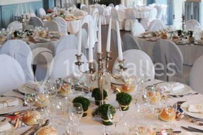 Des lanternes lumineuses flottent dans la nuit près d'une grande maison éclairée en bleu, entourée de personnes.